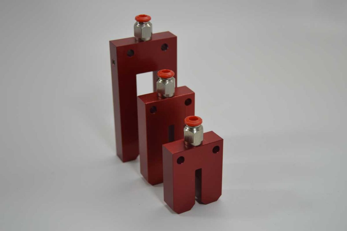 three industrial spray nozzles upright on a surface